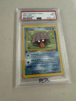 1999 POKEMON FOSSIL 1ST ED #54 SHELLDER PSA 9 - Image 1