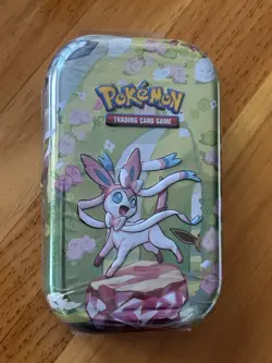 POKEMON TCG PRISMATIC EVOLUTIONS SYLVEON MINI TIN, 2 Booster Packs, 1 EEVEE Coin - Image 1